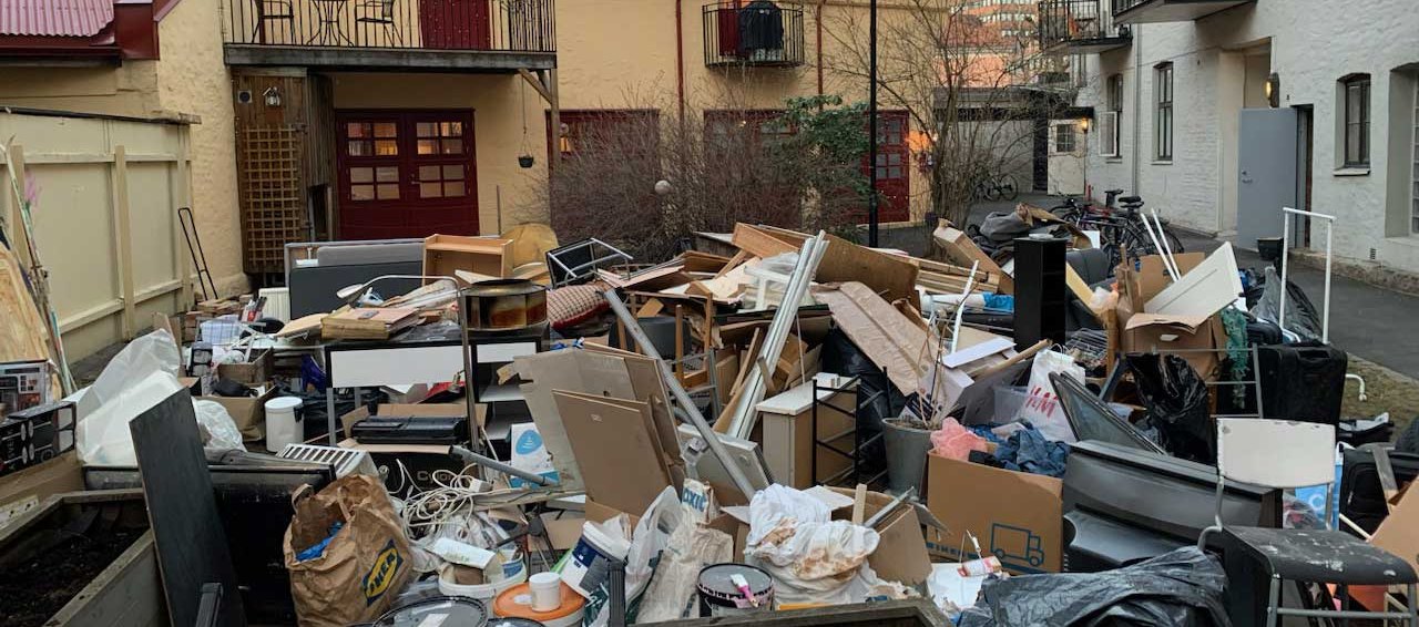 Stor haug med møbler, esker og grovavfall i en bakgård i Oslo, klar for henting